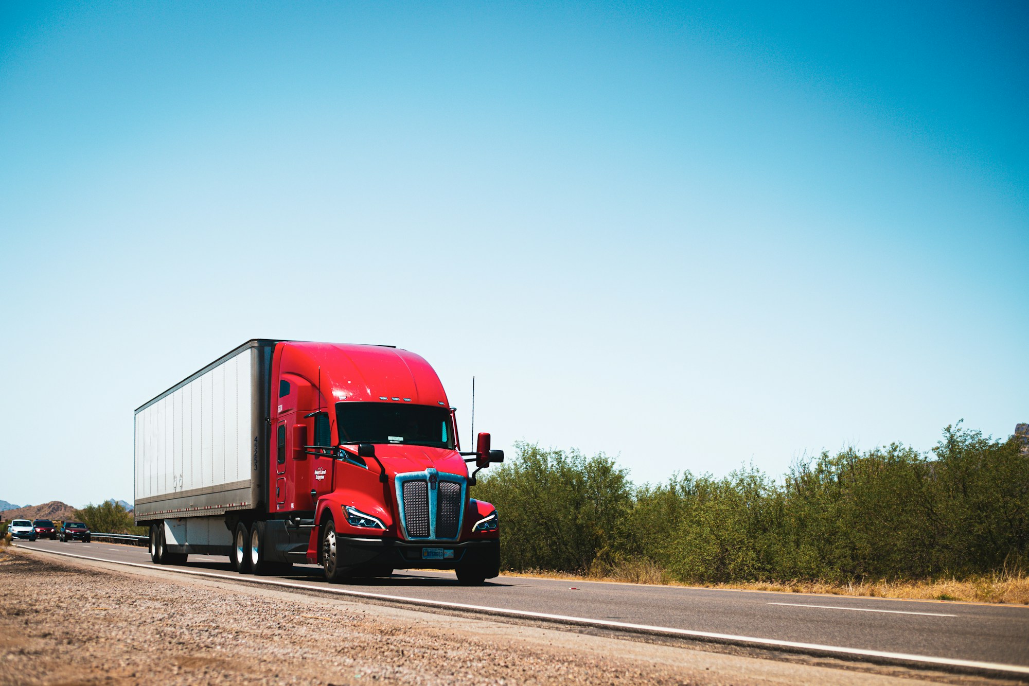 Red American semi-truck with a white trailer on an open road